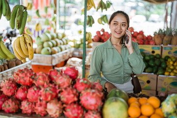beautiful customer calling on phone while buying the fruits at the fruit shop