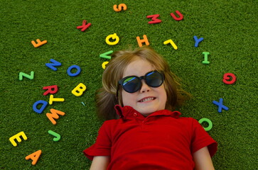 A preschooler plays with English letters. Learning the alphabet in kindergarten. The boy laughs - a...