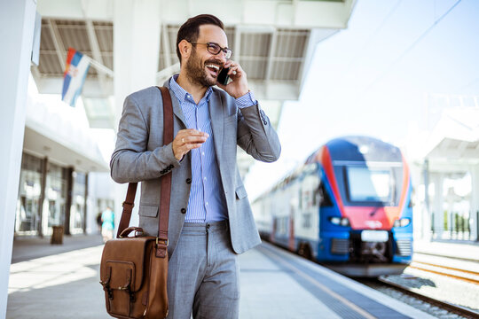 Man using mobile application on his smartphone at train station, business travel. Businessman with smartphone, waiting at the train platfo. Handsome bearded man is waiting for train