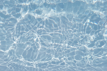 Blue water with ripples on the surface. Defocus blurred transparent blue colored clear calm water surface texture with splashes and bubbles. Water waves with shining pattern texture background.