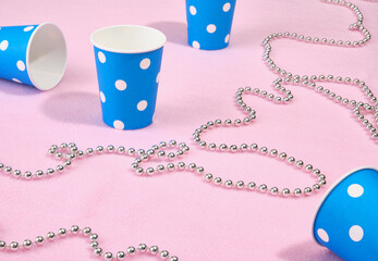 A festive composition of blue paper drinking cups and decorative beads.