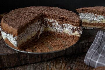 Fototapeta na wymiar Chocolate cream cake with bananas on dark wooden background