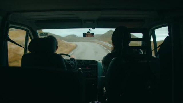 Rear seat handheld shot of couple travel inside camper van on cinematic Norwegian mountain road. Adventure road trip concept. Vanlife outdoor lifestyle. Life on the road