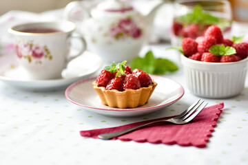 Mini tarts with raspberries served with tea on the table