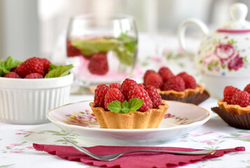 Mini tarts with raspberries served with tea on the table