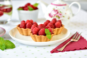 Mini tarts with raspberries served with tea on the table