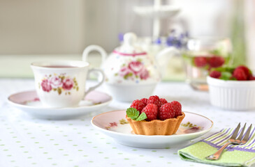 Mini tarts with raspberries served with tea on the table