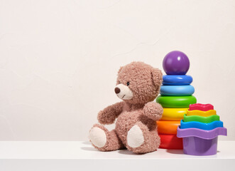 Toys for kids and play time. A soft funny teddy bear. Copy space for text. Pyramid with colored rings and ball, toys for sand.