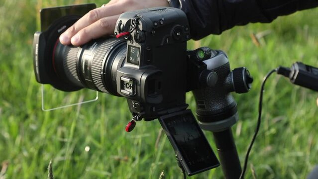 Photographer sets the shot on a camera mounted on a tripod and selects the focus, takes the picture with an intervalometer