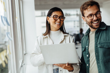 Business woman holding a laptop and standing with her colleague