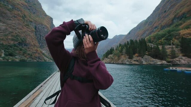 Portrait of female photographer adjust settings on professional camera, shoot landscape travel photography. Adventure or travel blogger, social media creator or vlogger in Northern Europe