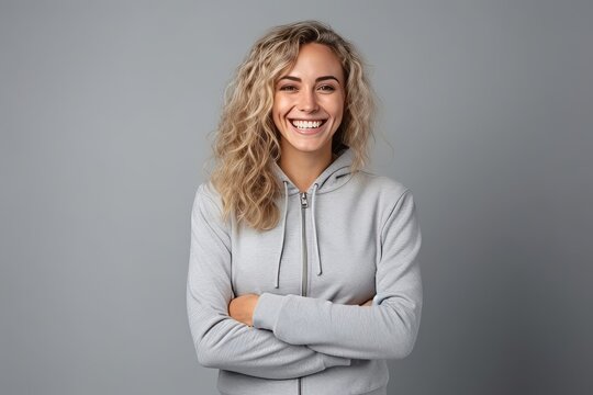 Portrait Of Smiling Young Woman With Crossed Arms Isolated On Grey Background