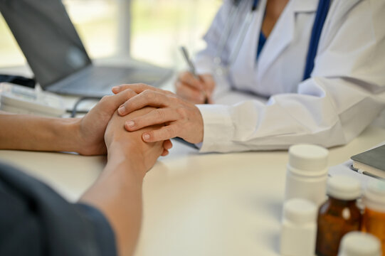 Close-up image of a doctor touching a patient's hands to reassure him during the medical checkup