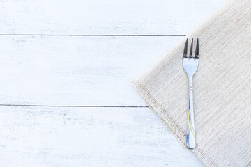 Dessert fork on fabric placemat with space on white wooden table background, kitchen utensil, dining table