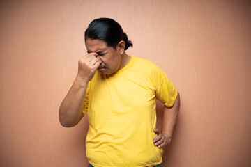 old asian man suffering from headache with right hand on forehead in plain background isolated