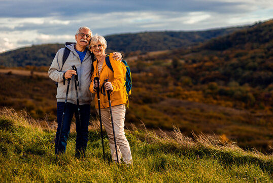 Portrait Of Active Senior Couple With Backpacks Hiking Together In Nature On Autumn Day.