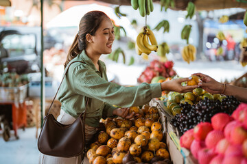 female customer giving the passion fruit to the seller at the fruit shop