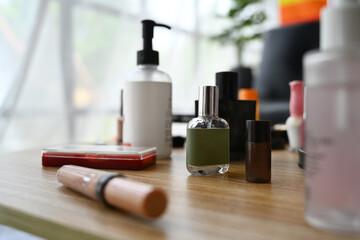 Closeup view of skincare product, lotion bottle, round mirror and makeup brushes on dressing table