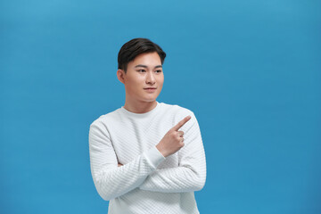 Cheerful young Asian man pointing fingers at copy space, advertisement banner