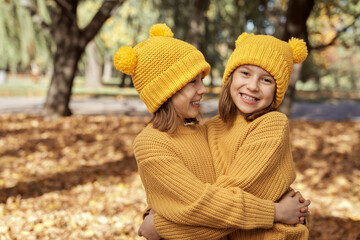 Portrait of child siblings standing in the park and wearing yellow hats