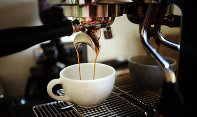 Close-up of espresso pouring from the coffee machine into a coffee cup. Professional coffee brewing