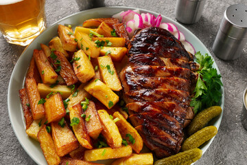 American lunch with juicy steak and beer, served with french fries, radishes and herbs