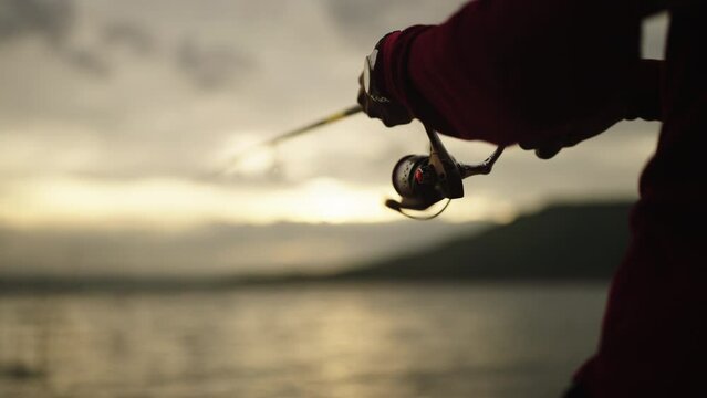 Silhouette of a fisherman with a fishing pole at sunset and enjoying hobby, catch of fish