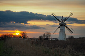 Plakat Beautiful orange sunset lighting up the clouds over Thurne Dyke Drainage Mill set in The Broads, near Great, Yarmouth, Norfolk, UK