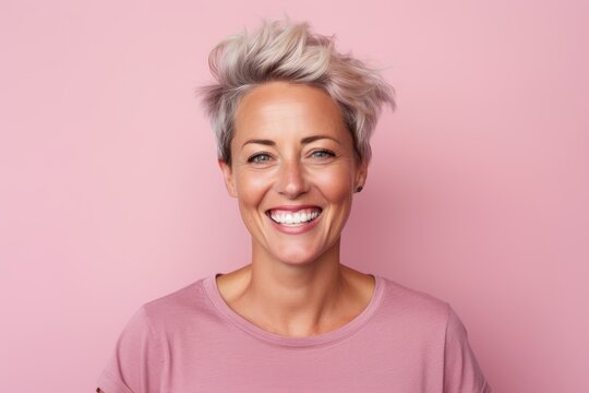 Portrait Of A Smiling Middle-aged Woman With Short Blonde Hair On A Pink Background