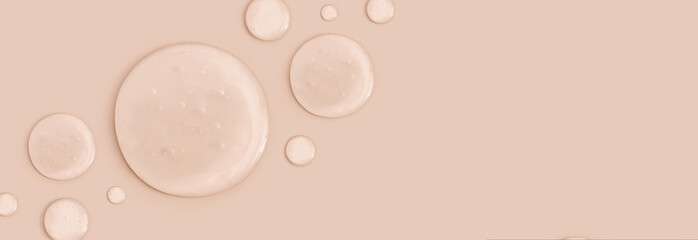 round drops of transparent gel serum on beige background	
