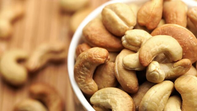Cashew Pieces on a turntable from overhead. Plant based ingredient. Dried cashew nuts. Macro shot. Raw snack. Pile cashew nuts without shell, rotates, close up. Whole nut kernels. Rotation