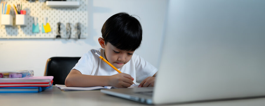 Asian Kid Boy Focused On Homework And Learning Alone In Room At Home, Serious Asian Kid Concentrating On Homework, Studying And Success, Homework And Education Of Asian Kids Concept In Banner Size.