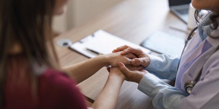Happy woman visiting doctor senior , getting optimistic news after medical checkup, therapy. Therapist holding hand of patient, giving hope, support, congratulating on goor treatment result
