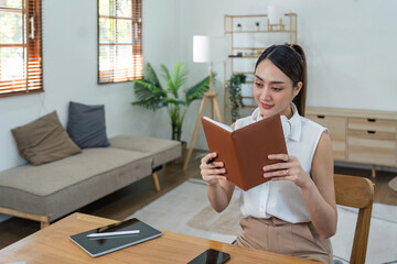 Obraz premium Attractive young woman sits in and comfortable living room enjoying reading a book