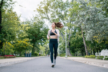 Asian beautiful woman running in a park for health, wellness and outdoor exercise. Nature, sports and female athlete runner doing cardio workout in garden. Healthy Concept.