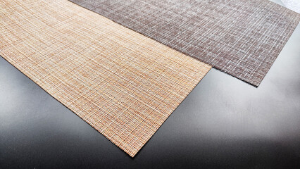 Brown and beige textured napkins, similar in weave to burlap on a black surface. Background, texture, frame and copy space. The concept of beautiful decor and comfort in the house