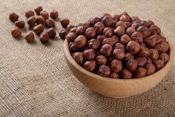 View of a bowl full of peeled hazelnut on burlap sack
