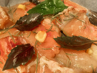 Marinated fish in near plan with rosemary and basil