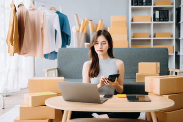 Startup small business SME, Entrepreneur owner woman using smartphone or tablet taking receive and checking online purchase shopping order to preparing pack product box. .