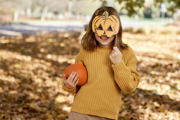 Portrait of girl standing in the woods and holding photo booth accessory and a pumpkin