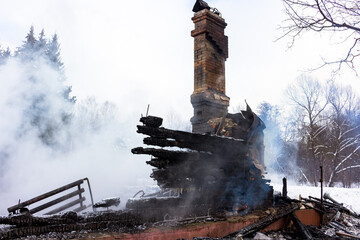 Smoke on the ashes, brick chimney in smoke after a fire in a wooden building