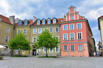 Fototapeta na wymiar Old architectural buildings with colorful walls. Cityscape with houses. Trees around. Summer sunny day with blue sky. Poland, Poznan, June 2022