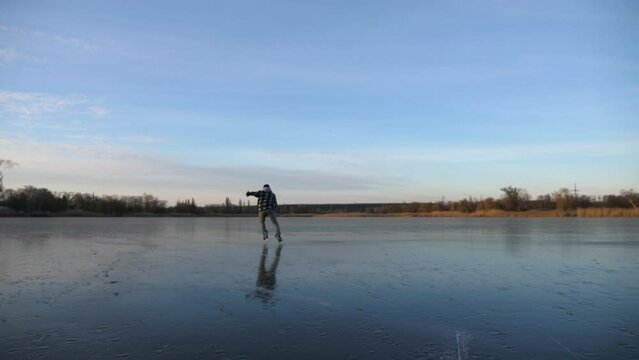 Young man in figure skates sliding fast on ice during training. Guy skating on frozen river. Male hockey player accelerates to top speed at skates. Active leisure at cold winter day. Slow motion