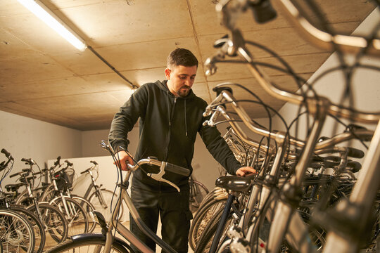 Serious man checking bike while preparing repairing it at the bicycle workshop