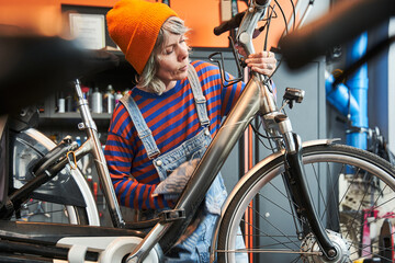 Serious woman technician wiping bicycle at shop sells