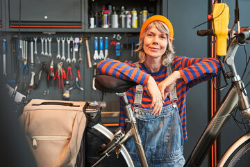 Smiling woman technician posing with bicycle at shop sells - 622626955