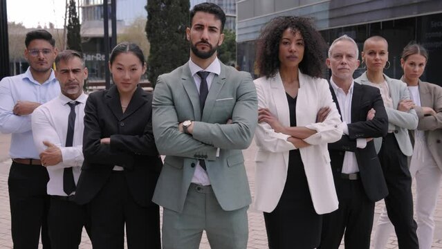 Team portrait multi-ethnic professionals posing confidence. Young and mature colleagues looking at camera crossing arms serious expression. Group of office workers indoor a startup business company.