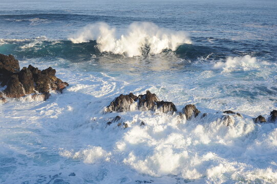 strong waves breaking and crushing on the volcanic rocks on the Atlantic Ocean on coastline and seashore of Madeira Island, Portugal, Europe