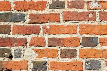 Wall of antique handmade baked bricks with cracks and holes