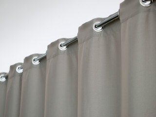 Heavy thick gray curtain with grommets on the stainless tube of the cornice